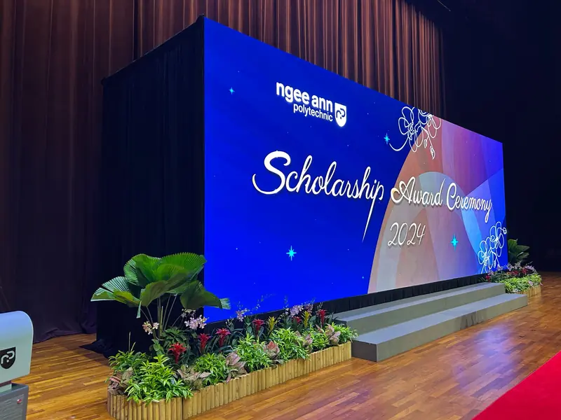 Award ceremony stage with an LED wall behind a riser lined with plants