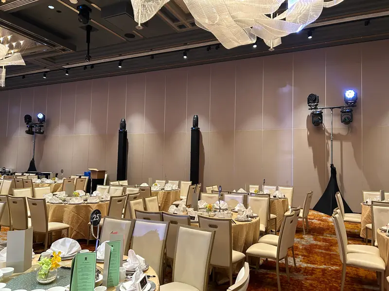 Moving head lights on stands around a ballroom set for dinner