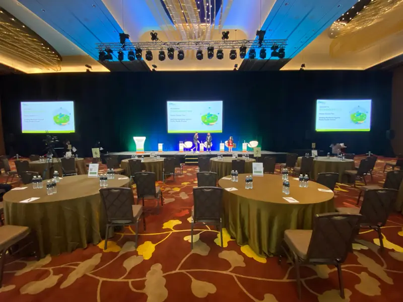 Lighting truss over three screens and dinner tables in a ballroom