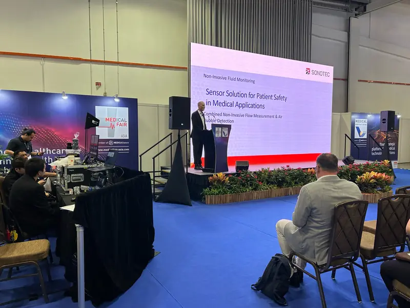 Speaker at a lectern on a conference stage, with the technical desk set beside it
