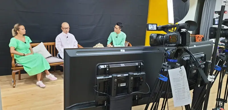 Three guests on a studio sofa, filmed with a camera and a preview monitor
