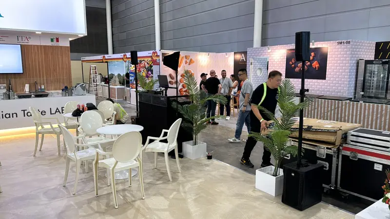 Exhibition booths with speakers on stands and equipment cases