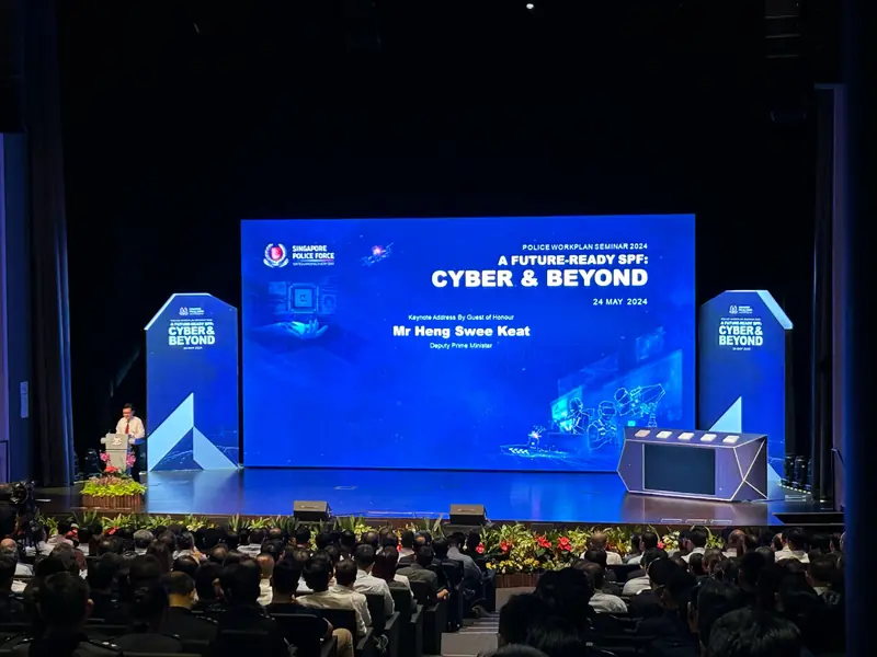 Seminar in an auditorium, a speaker at the lectern beside a large LED wall