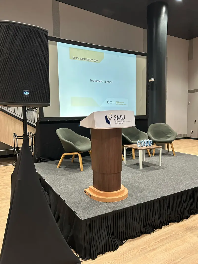 Carpeted stage riser with skirting, a lectern and a speaker on a stand
